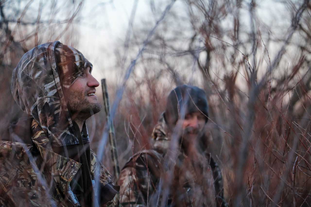 two hunters in tall brambles at dawn