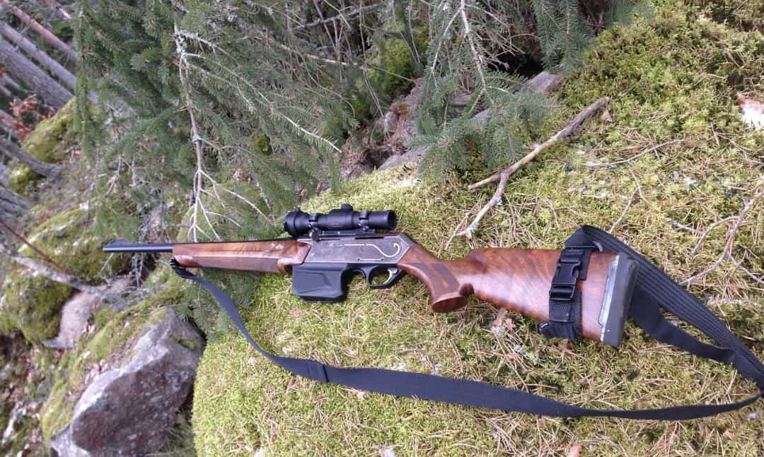 Rifle resting on a grassy rock